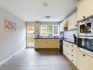 uma grande cozinha com armários amarelos e uma janela em Luxury Accommodation with TVs in each Room em Macclesfield