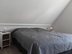 ein weißes Schlafzimmer mit einem Bett und zwei Lampen in der Unterkunft Nice holiday home with garden, on a holiday park 200m from the beach in Wemeldinge