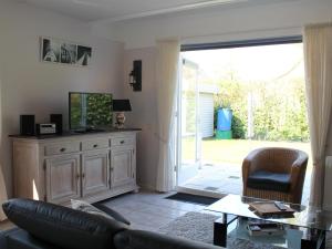 ein Wohnzimmer mit einem Sofa und einer Glasschiebetür in der Unterkunft Nice holiday home with garden, on a holiday park 200m from the beach in Wemeldinge