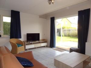 ein Wohnzimmer mit einem Sofa und einem TV in der Unterkunft Nice holiday home with WiFi, on a holiday park 200m from the beach in Wemeldinge