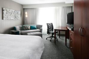 a hotel room with a bed and a chair and a desk at Courtyard by Marriott Omaha Aksarben Village in Omaha