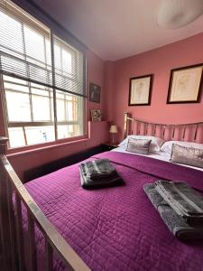 Dormitorio rosa con cama grande con sábanas moradas en Green Dragon LUDLOW en Ludlow