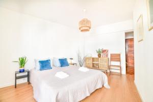 a white bedroom with a large white bed with blue pillows at Casa da Raposa by MOJE Holiday in Lagos +5 photos