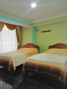two beds in a room with green walls at HOTEL LA 7MA AZUL in Pasto