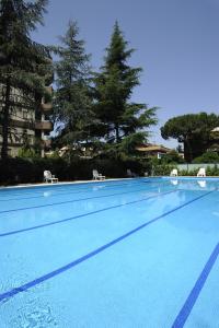 una gran piscina con 2 sillas y árboles en Residence Parco Salario, en Roma