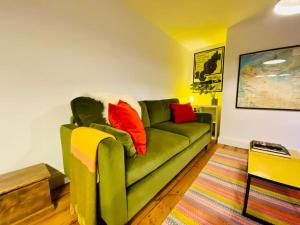un soggiorno con divano verde e cuscini rossi di Stylish Garden Flat a Deal