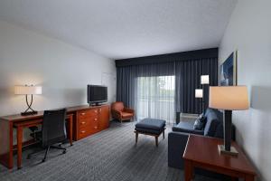 a hotel room with a couch and a desk and a television at Courtyard by Marriott Dallas Arlington Entertainment District in Arlington