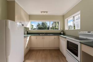 a kitchen with white cabinets and a large window at Charming Hideaway in Taupo