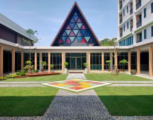 a large building with a garden in front of it at The Cotton Tree Hometel in Khon Kaen