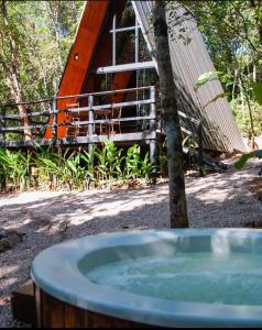 uma banheira de hidromassagem em frente a uma árvore e a uma casa em Sítio Aroeira Cabanas em Sao Jorge