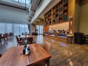 a dining room with wooden tables and chairs at The Cotton Tree Hometel in Khon Kaen