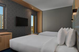 a hotel room with two beds and a television at Aloft Aberdeen TECA in Aberdeen