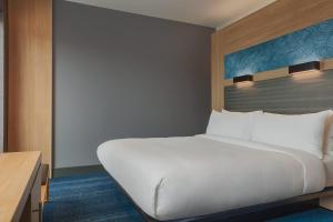 a bedroom with a large white bed and a desk at Aloft Aberdeen TECA in Aberdeen