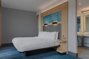 a bedroom with a large white bed and a kitchen at Aloft Aberdeen TECA in Aberdeen
