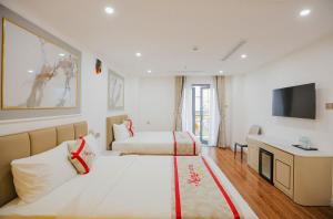 ニャチャンにあるKana Hotel Nha Trangのベッド2台とテレビが備わるホテルルームです。