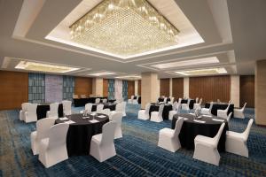 une salle de conférence avec des tables et des chaises ainsi qu'un lustre dans l'établissement Fairfield by Marriott Agra, à Agra