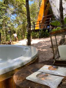 a bath tub sitting on a table next to a tree at Sítio Aroeira Cabanas in Sao Jorge