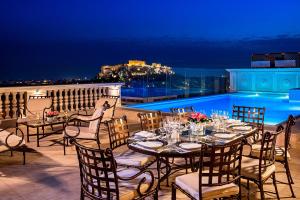 una mesa y sillas en un balcón por la noche en King George, a Luxury Collection Hotel, Athens, en Atenas
