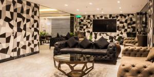 Rasia Hotel Jeddah في جدة: غرفة معيشة مع أريكة وتلفزيون