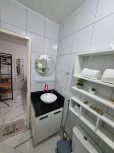 a white bathroom with a sink and a mirror at Cobertura no Centro da Cidade in Campina Grande