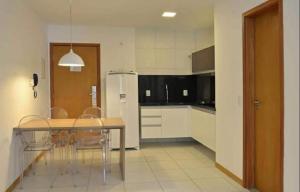 a kitchen with a table and chairs and a refrigerator at Residencial ILOA in Barra de São Miguel