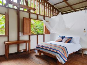 1 dormitorio con 1 cama en una habitación con ventanas en Reserva Pakore Wera, en Bahía Solano