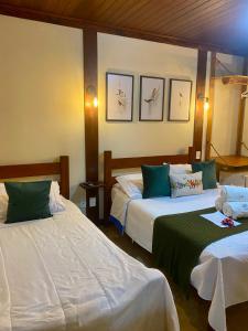 una camera d'albergo con due letti di colore verde e bianco di Pousada do Figa a Visconde De Maua