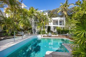 a swimming pool in front of a building with palm trees at 5 76 Upper Hastings Street in Noosa Heads