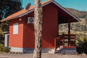 un edificio rojo con un árbol delante de él en Pousada Lago da Colina, en Urubici