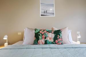 Bett mit Blumenkissen darüber in der Unterkunft Sea Foam Villas in Port Campbell