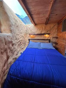 a bedroom with a blue bed in a rock wall at casa de los picapiedra in Sesquilé