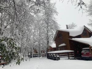 a snow covered house with a car parked in front of it at Cabañas Bordenieve in Las Trancas