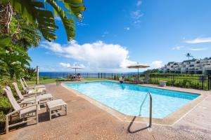 een zwembad met stoelen en uitzicht op de oceaan bij Puu Poa Ocean Bluff Condo, Incredible Views, Walk to Beaches, Pool & Tennis in Princeville