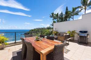 a wooden table and chairs on a patio with the ocean at Puu Poa Ocean Bluff Condo, Incredible Views, Walk to Beaches, Pool & Tennis in Princeville