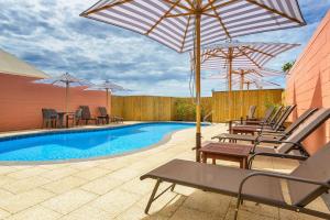 a patio with chairs and umbrellas and a pool at Osprey Holiday Village Unit 104 in Exmouth