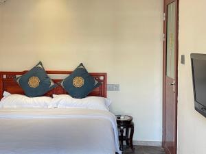 北京市にある北京 ハイド コートヤード ホテルのベッドルーム(青い枕のベッド1台、テレビ付)