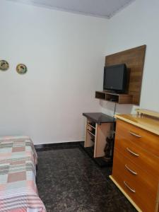 ein Schlafzimmer mit einem Bett und einer Kommode mit einem TV in der Unterkunft Casa com quarto e suíte in São Miguel Arcanjo
