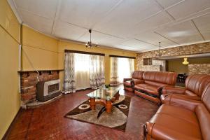 a living room with leather furniture and a tv at Macum Haven Florida Park in Roodepoort