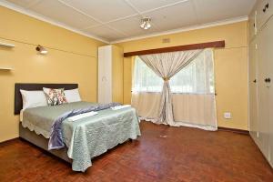 a bedroom with a bed and a window at Spacious Holiday Home in Florida Park! Pool! Parking! Fast Wifi! in Roodepoort