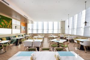 una sala da pranzo con tavoli, sedie e finestre di Home2 Suites by Hilton Beijing Shunyi a Shunyi