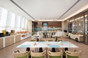 cocina y comedor con mesas y sillas en Home2 Suites by Hilton Beijing Shunyi, en Shunyi