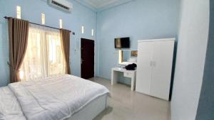 Dormitorio azul con cama y ventana en OYO 92701 Jasmine House Syariah, en Pekanbaru