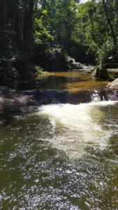a river with a waterfall in a forest at Casa do Cedro - Sítio Cascatinha in Cruzeiro