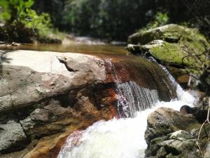 a small waterfall in a river with rocks at Casa do Cedro - Sítio Cascatinha in Cruzeiro