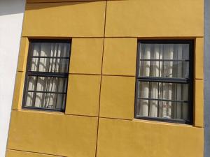 dos ventanas en el lateral de un edificio amarillo en Michelle's Place (Entire House), en General Trias