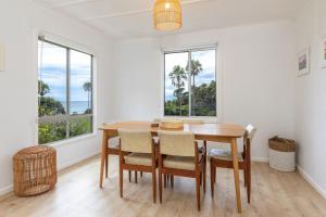a dining room with a table and chairs and windows at Trade Winds in Elizabeth Beach
