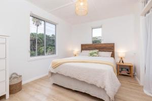 a white bedroom with a bed and two windows at Trade Winds in Elizabeth Beach
