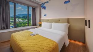 a bedroom with a large bed and a large window at Lanz International Hotel Shenzhen Guangming Wisdom City in Tiantangwei