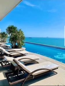 a row of chaise lounge chairs on a swimming pool at A sea view beautiful studio apartment in Nha Trang
