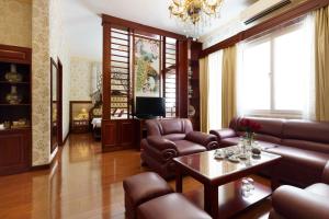 Victory Sai Gon Hotel في مدينة هوشي منه: غرفة معيشة بأثاث جلدي وثريا